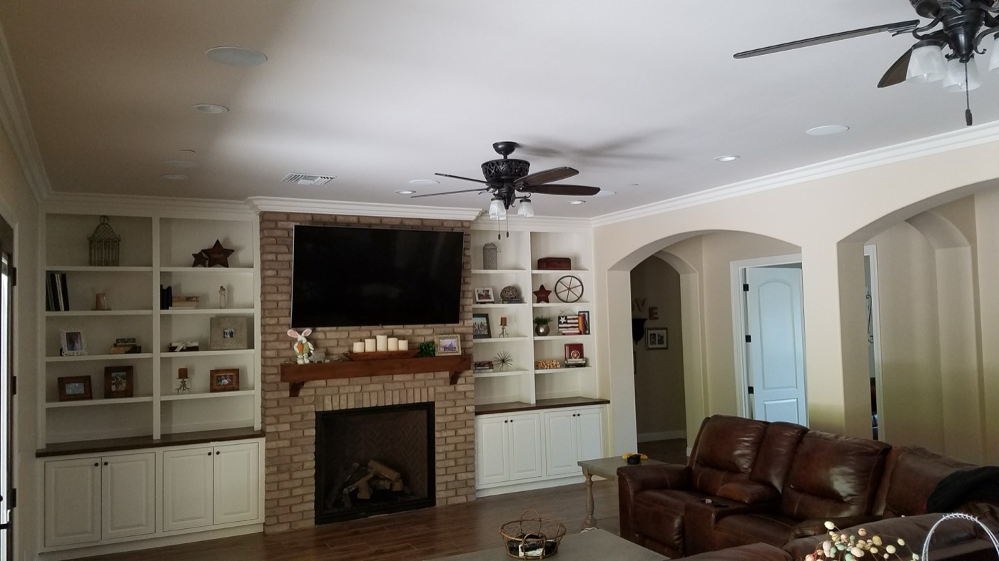 TV mounted above a brick fireplace with built-in bookshelves in a family room