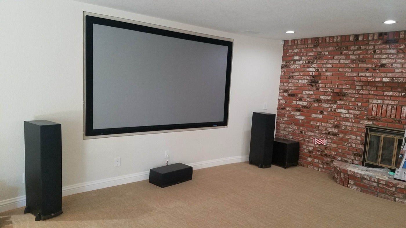 Dedicated home theater installation with projector screen and floor-standing speakers