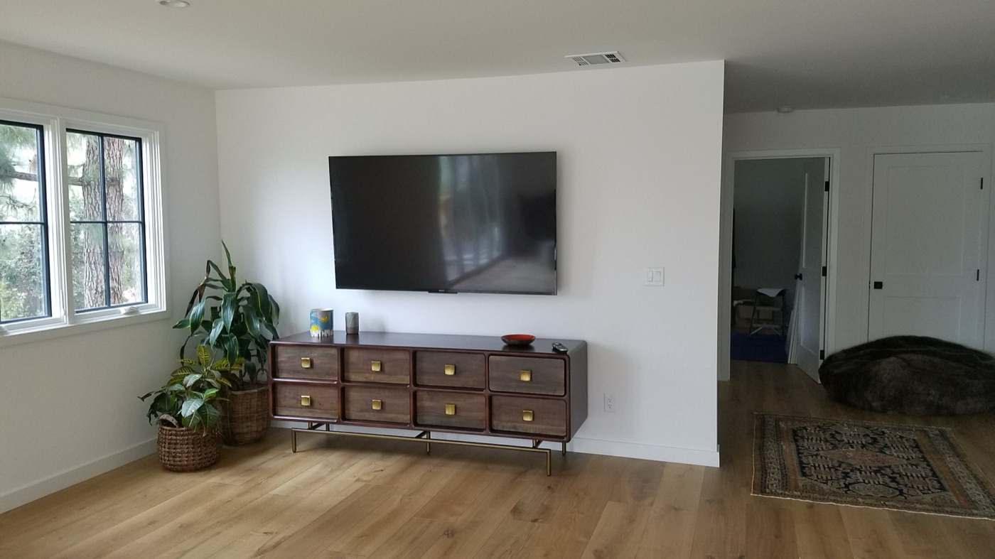 TV mounted securely above a credenza in a bright living room with concealed cabling